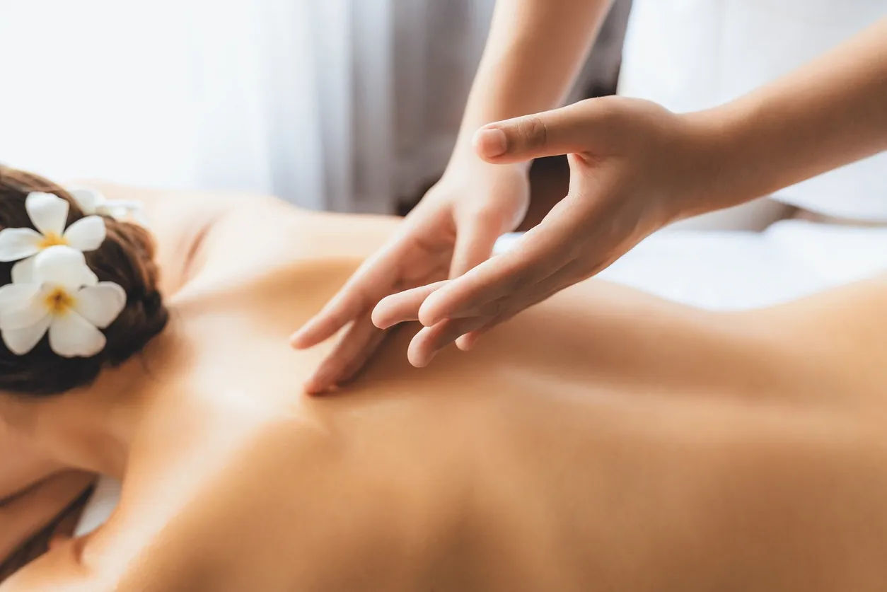 mujer en spa recibe masaje con flores en cabello